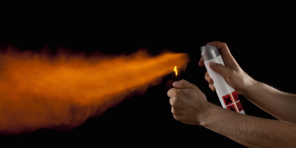 A hand igniting the spray from an aerosol can