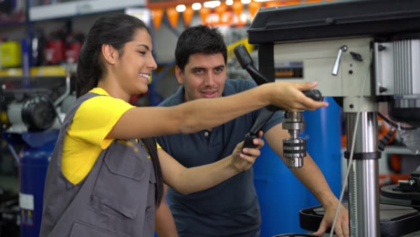 Saleswoman explaining to a male customer how to use a machine tool both smiling and looking happy