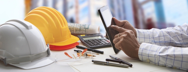 hand of architect working on table with tablet computer and working tool equipment against reflection of office building and crane construction for civil engineering and construction industry business