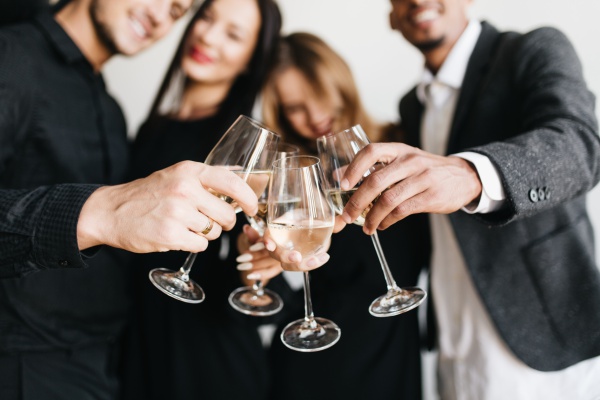 Indoor portrait of romantic blonde girl chilling at friend's party and posing with glass full of champagne. Relaxed young people in stylish outfit drinking wine during meeting and joking.