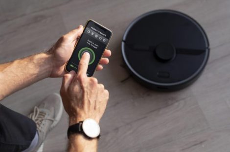 man-controlling-robot-vacuum-with-his-phone