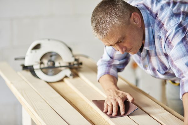 Carpenter is sanding wooden materials