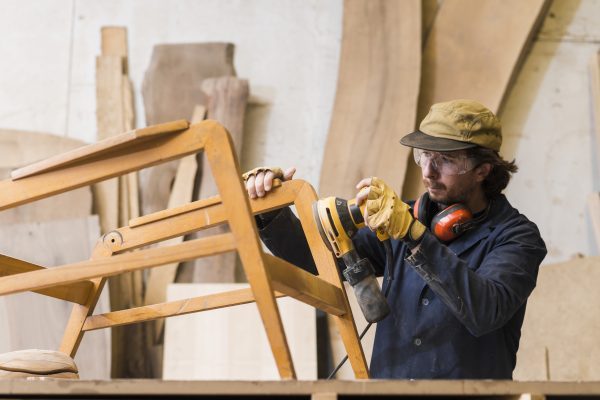 male-carpenter-sanding-wood-with-orbital-sander-in-workshop