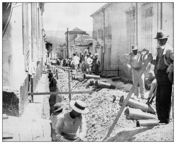 Antique black and white photograph of people from islands in the Caribbean and in the Pacific Ocean; Cuba, Hawaii, Philippines and others: Laying drain pipes in Santiago de Cuba